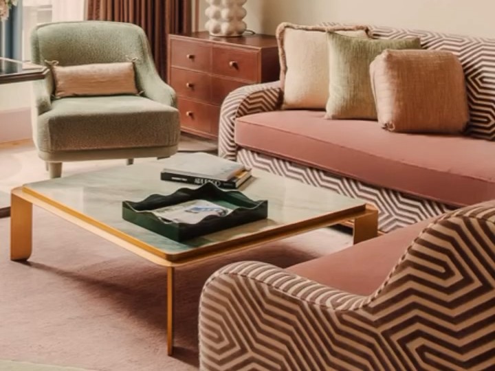 Suite living room at Fouquet’s New York with a sage armchair, blush sofa with chevron upholstery and a brass-framed coffee table